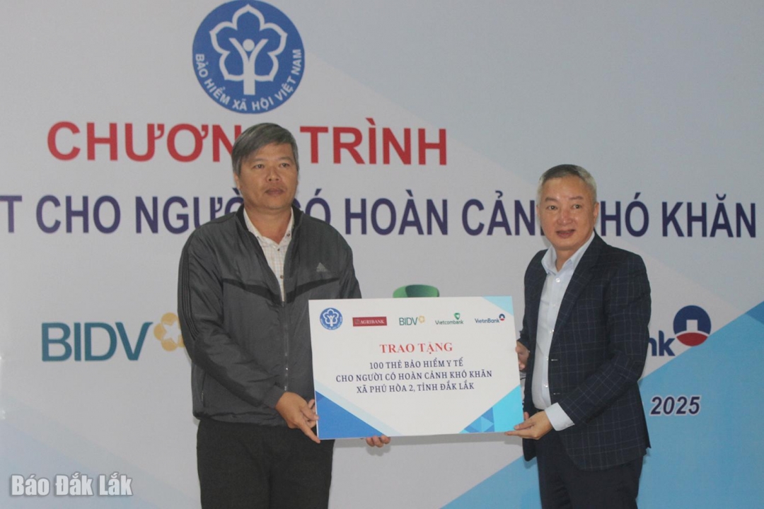 Ông Trần Mạnh Toàn, Giám đốc Bảo hiểm xã hội tỉnh (phải) trao biểu trưng tặng 100 thẻ bảo hiểm y tế cho người dân xã Phú Hòa 2