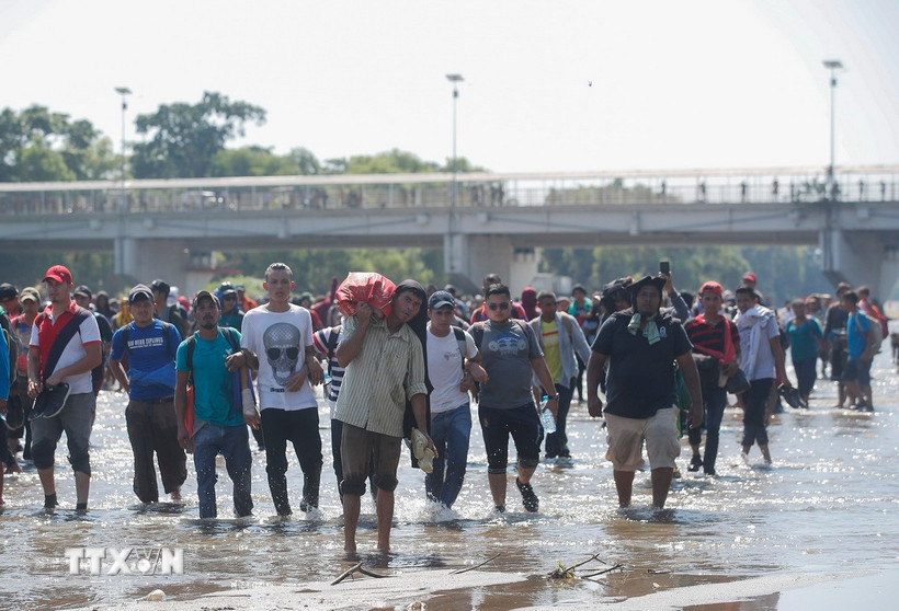 Người di cư Trung Mỹ vượt sông Suchiate từ Guatemala để tới Mexico, trong hành trình đến Mỹ. Ảnh: TTXVN