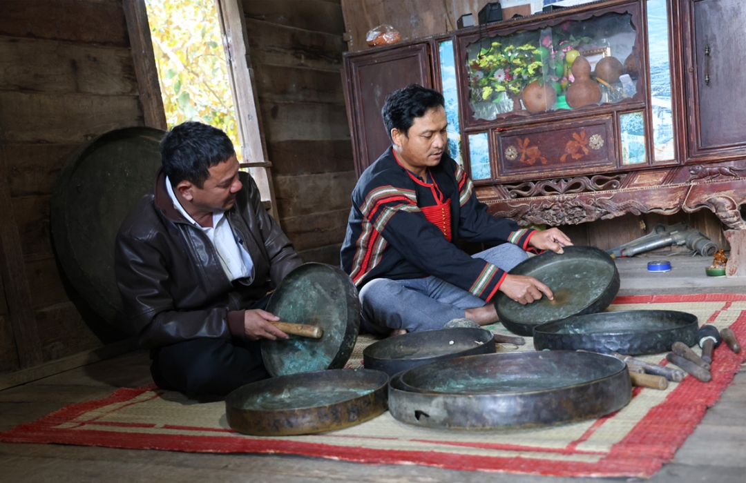 Ông Y Phương Niê (bìa phải) chia sẻ về bộ chiêng cổ được gia đình ông gìn giữ.