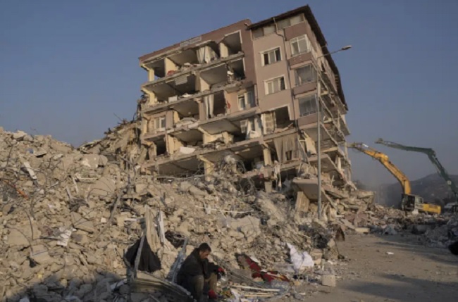 Một người đàn ông ngồi thẫn thờ trước đống đổ nát của tòa nhà bị đổ sập ở Antakya, Thổ Nhĩ Kỳ. Ảnh: AP/TTXVN