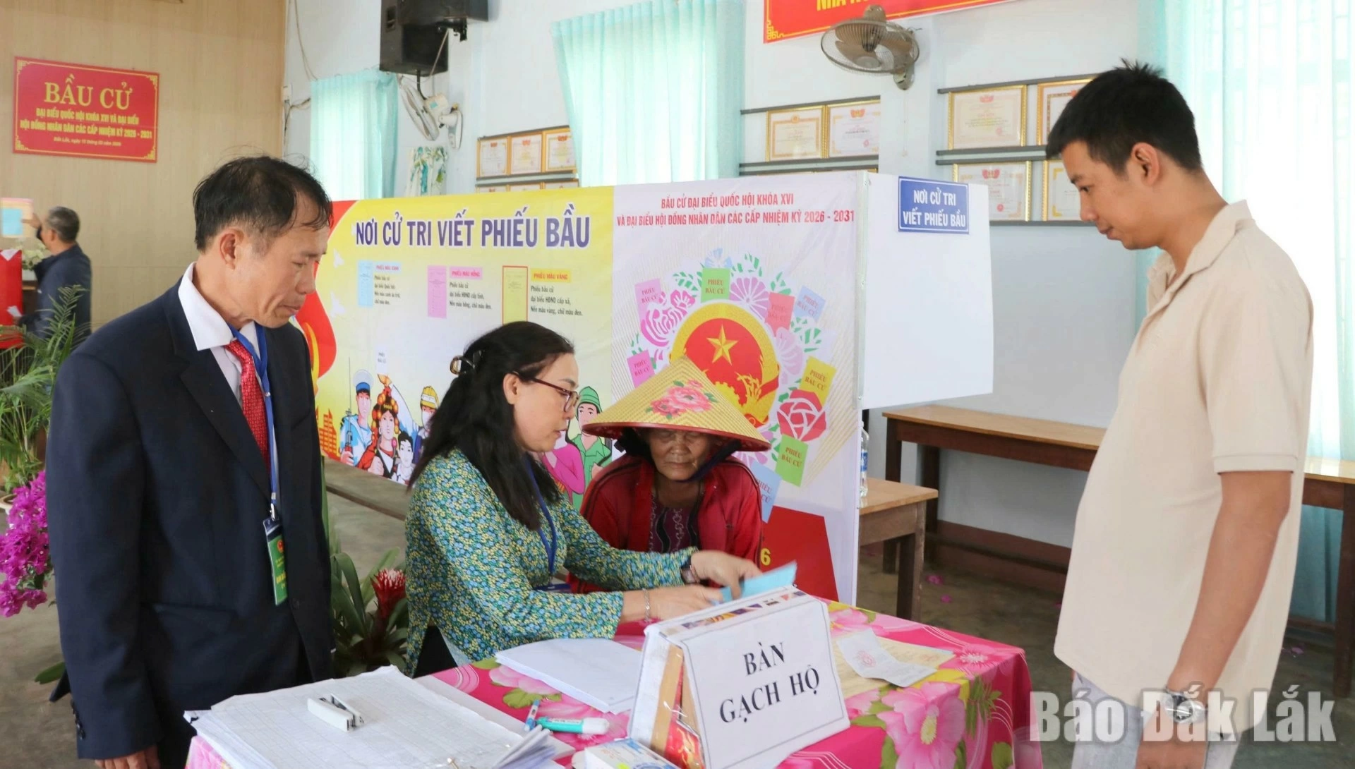 Ms. Ninh Thi Ngay of Tan Lap ward, who makes a living collecting scrap and cannot read, being assisted by election team members who read the list of candidates aloud so that she can choose before casting her vote.