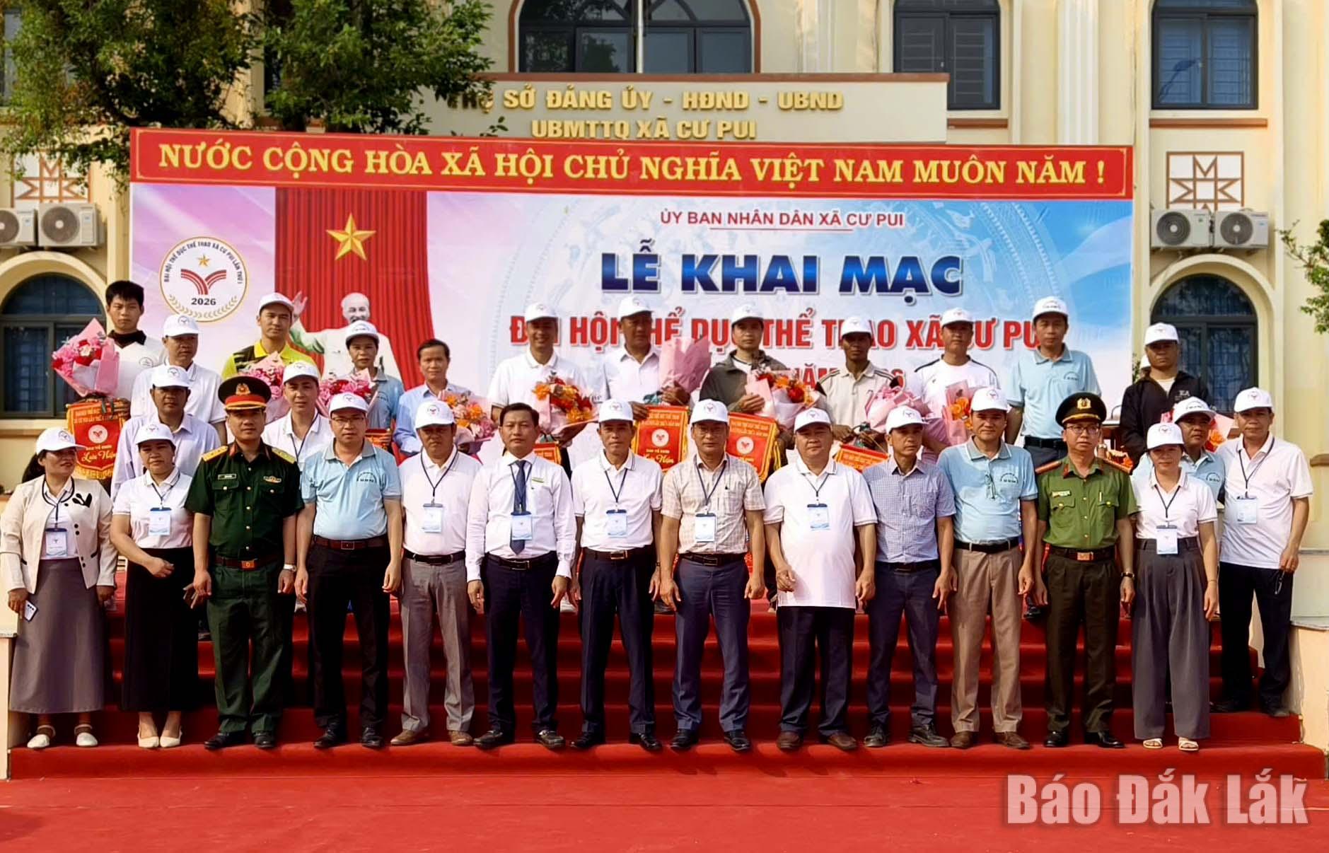 Lãnh đạo xã Cư Pui trao cờ lưu niệm vf chụp ảnh với đại diện các đoàn tham dự đại hội.