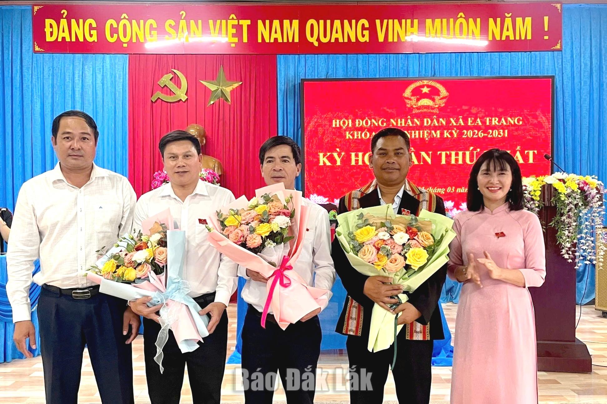 Đồng chí Y Nhuân Byă (bìa trái) và đồng chí Hòa Thị Hằng tặng hoa chúc mừng Chủ tịch UBND, các Phó Chủ tịch UBND xã Ea Trang.