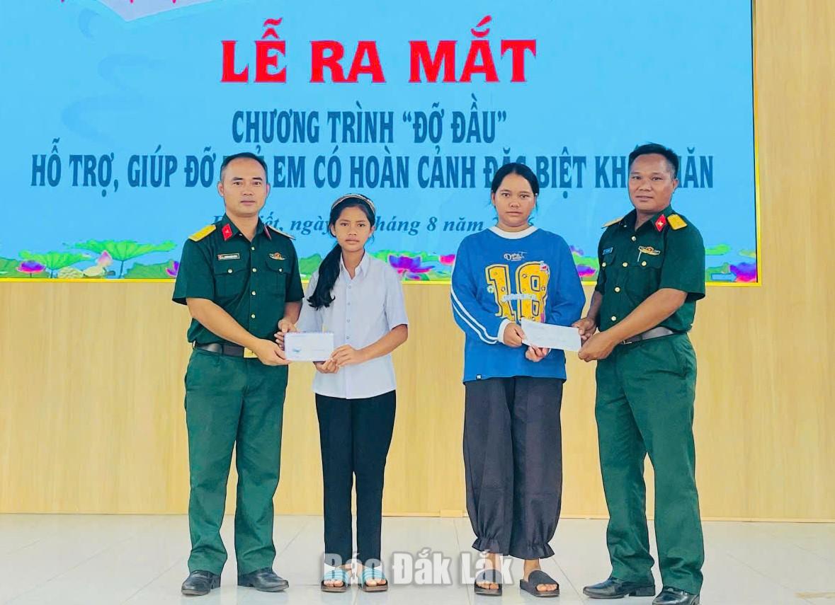 Em H’Cao Kđoh (thứ hai từ trái sang) và dì ruột nhận hỗ trợ từ Ban Chỉ huy Quân sự xã Ea Kiết.