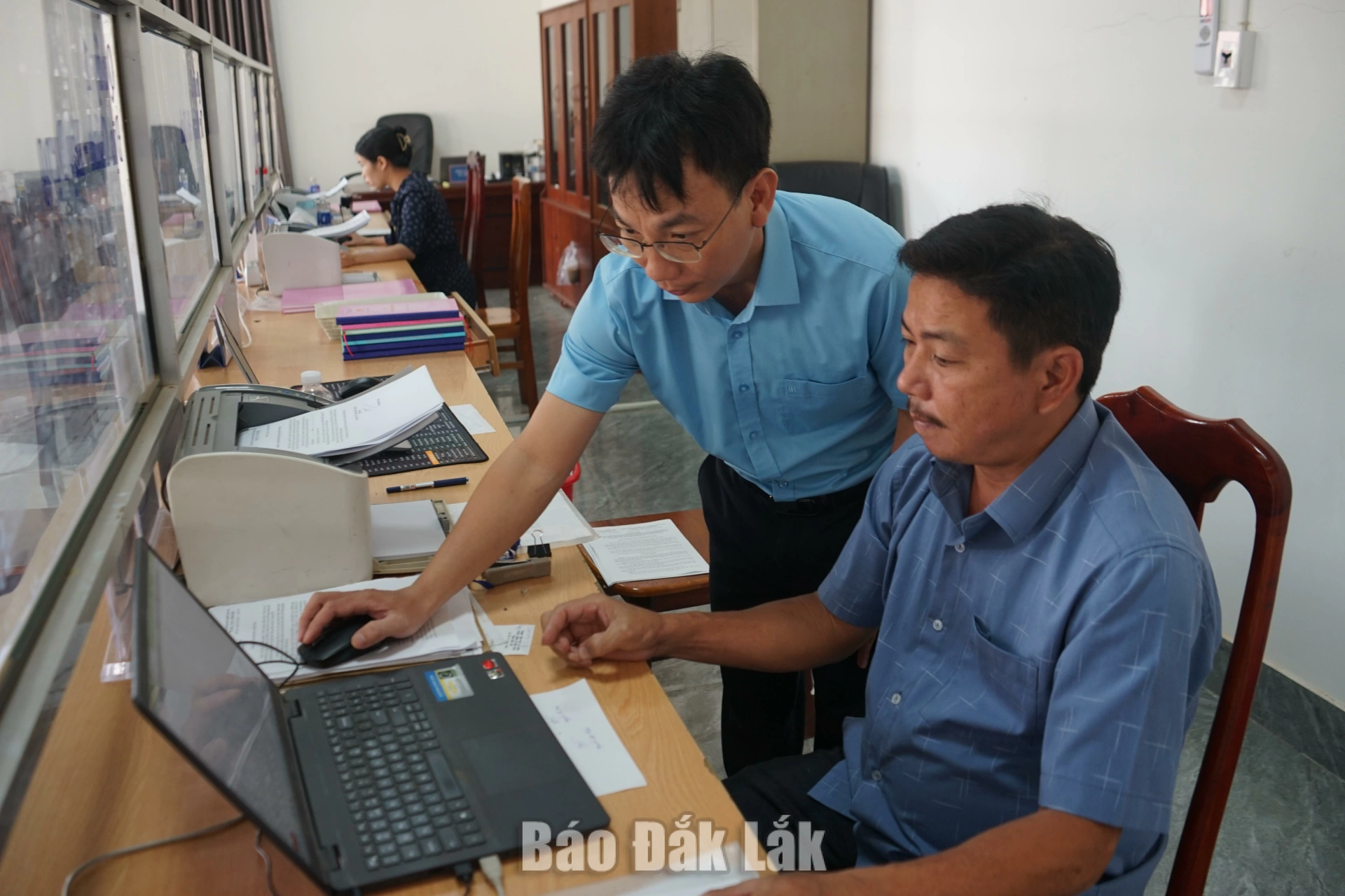 Anh Nguyễn Sỹ Vũ (bìa trái) hỗ trợ cán bộ Trung tâm Phục vụ hành chính công xã Đắk Phơi ứng dụng công nghệ thông tin. 