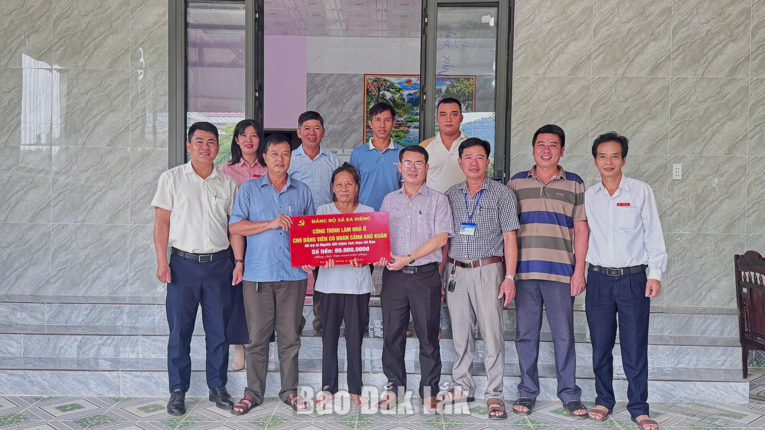 Lãnh đạo Đảng ủy xã Ea Riêng trao bảng tượng trưng tặng kinh phí xây nhà cho gia đình đảng viên Nguyễn Cao Cường. 