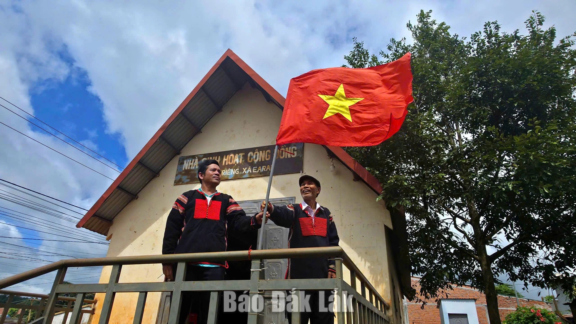 An influential figure and a village official hanging the national flag on National Day (September 2nd), helping to spread community solidarity spirit alongside pride.