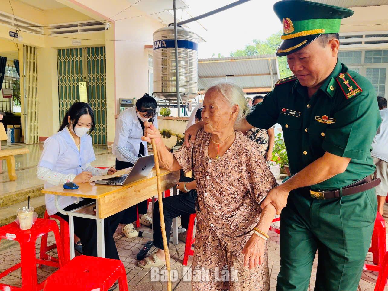 Cán bộ Đồn Biên phòng Cửa khẩu Đắk Ruê hỗ trợ người già đến địa điểm khám bệnh miễn phí.