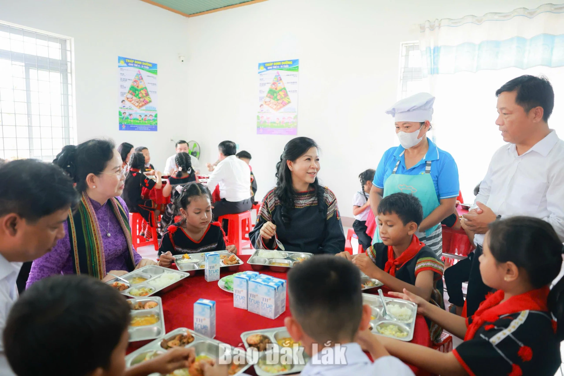 Các thành viên của đoàn công tác ăn cơm trưa cùng học sinh Trường Tiểu học và THCS Y Ngông Niê Kdăm (xã Đắk Phơi)