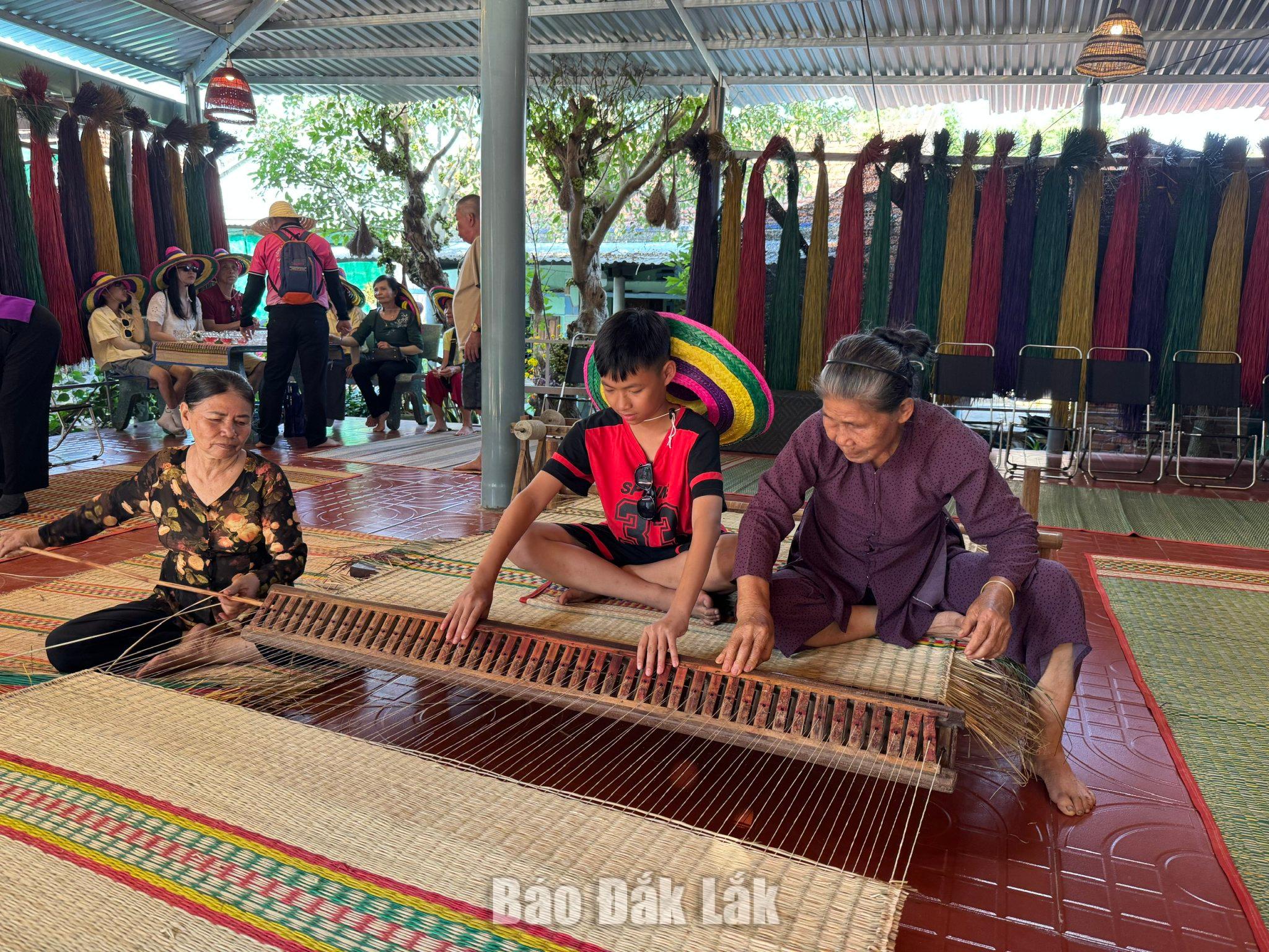 Visitors try their hand at weaving sedge mats at An Cu craft village in O Loan Commune.
