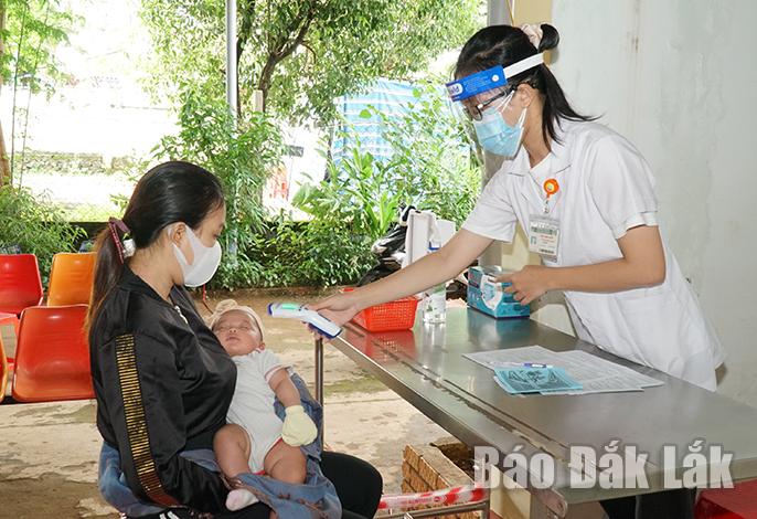 Người dân đưa trẻ đến tiêm chủng tại trạm y tế đều thực hiện khai báo y tế và kiểm tra thân nhiệt. 