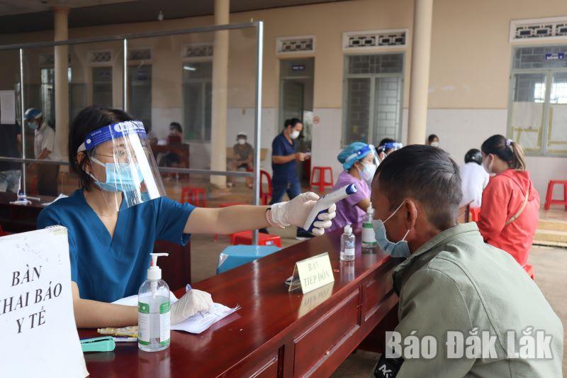 Nhân viên y tế kiểm tra thân nhiệt cho người dân trước khi tiêm vắc xin phòng COVID-19.
