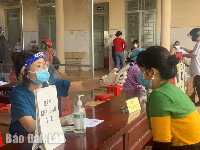 Nhân viên y tế kiểm tra thân nhiệt cho người dân trước khi tiêm vắc xin phòng COVID-19.