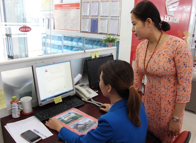 Cán bộ thuế hướng dẫn một người nộp thuế ở huyện Ea Kar thực hiện hoá đơn điện tử