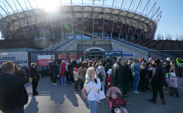 Người tị nạn Ukraine xếp hàng chờ đợi tại Sân vận động Quốc gia ở Warsaw xin cấp mã số để làm việc và sử dụng miễn phí dịch vụ chăm sóc sức khỏe, giáo dục. (Ảnh: AP/TTXVN)