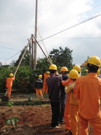 Công nhân Điện lực Dak Lak đang cẩn trọng di chuyển trụ điện trong thi công để không ảnh hưởng đến cây trồng của người dân.