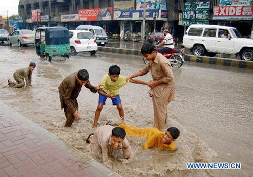 Trẻ em chơi đùa trên đường phố ngập nước ở Peshawar, Pakistan