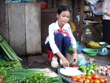 Em Bùi Thị Quỳnh Trang tranh thủ lúc đi học về ra chợ bán rau giúp mẹ.