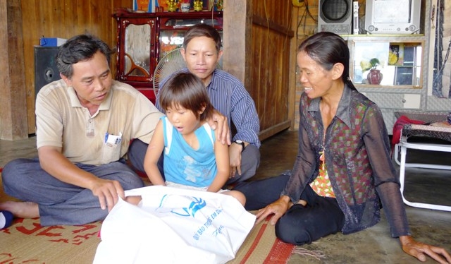 Anh Nguyễn Văn Hưng (trái) thăm và tặng quà cháu Hoàng Thị Thùy Trang vừa mổ tim ở thôn 6, xã Cư Kty.