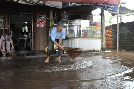 Vợ chồng ông Nguyễn Quang Châu đang tát nước trên nền nhà vào trưa 10-10