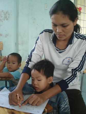 Lấy ghế làm bàn, cô H’ Mit Kbua cùng các cháu trường Mầm non Hoa Lan vẫn say sưa theo từng nét chữ