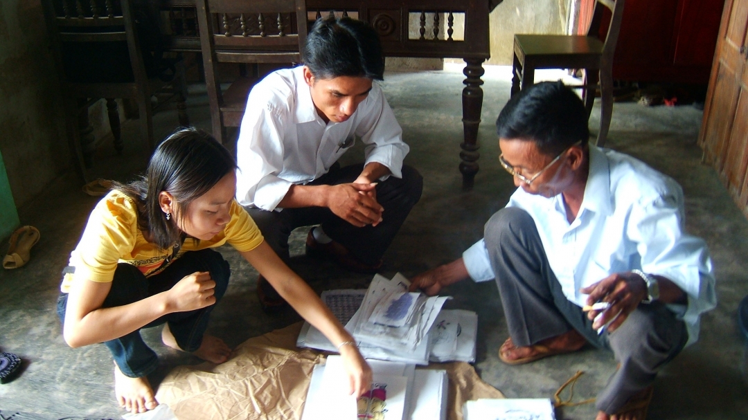 Nghệ nhân Kỳ Hữu Phước đang giới thiệu  bộ tranh Làng Sình truyền thống. 