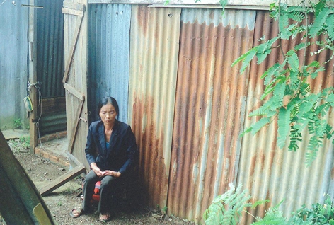 Bà  Trần  Thị Luyện  bên chiếc lán tạm  làm  trên  đất vườn người khác. 
