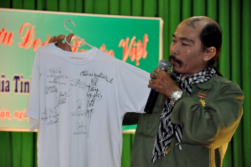 Nghệ sĩ Quang Đạt đang giới thiệu chiếc áo có nhiều chữ ký của các nghệ sĩ nổi tiếng