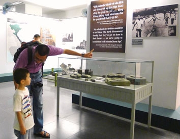 Một du khách Hàn Quốc đang thuyết minh cho con trai mình về những bức ảnh và hiện vật tàn khốc của chiến tranh.