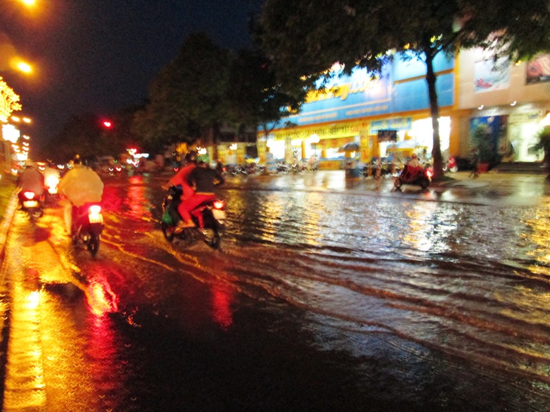 Người dân đi xe máy trên đường Nguyễn Tất Thành phải đi sát vào giải phân cách để tránh nước