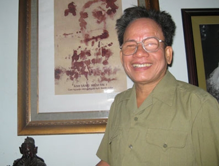 Đại tá, họa sĩ Lê Duy Ứng bên bức huyết họa      chân dung Bác Hồ.                                Ảnh: T.L