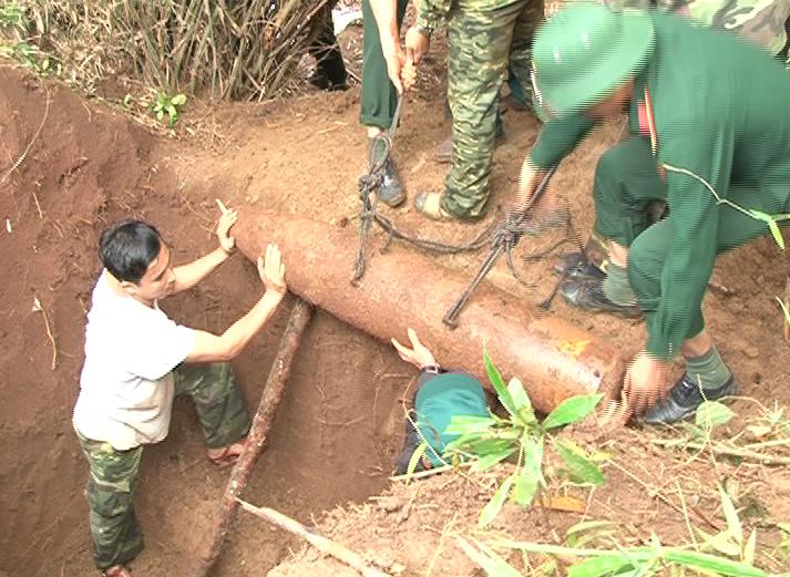 Lực lượng chức năng đưa quả bom xuống hố chuẩn bị phá hủy