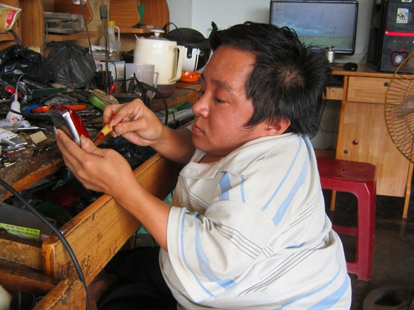 Anh  Lê Sỹ Tuấn đang  sửa máy nghe nhạc cho  khách hàng.