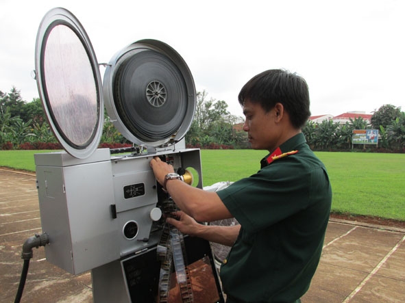  Trung úy chuyên nghiệp Trương Huy Thái ráp phim vào máy, chuẩn bị  trước cho buổi chiếu phục vụ cán bộ, chiến sĩ, bà con buôn làng.