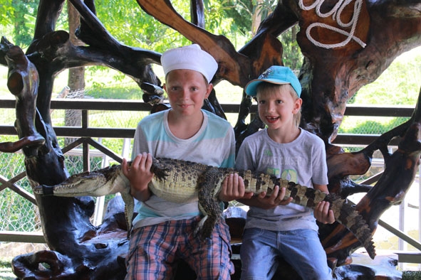 Du khách nước ngoài tham gia chụp hình lưu niệm với cá sấu sống.
