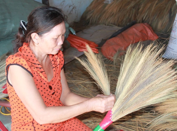 Bà Phạm Thị Thơm đang thực hiện những khâu cuối cùng  để hoàn thiện một cây chổi.
