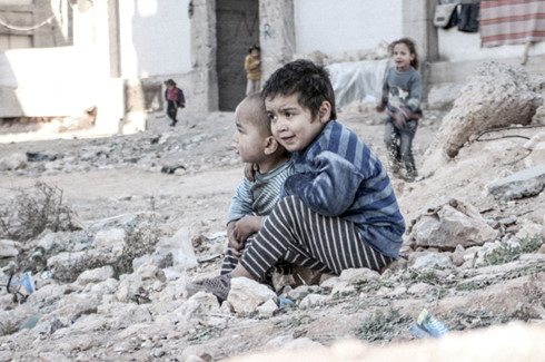 Cậu bé 4 tuổi Esraa và em trai Waleed, 3 tuổi, ngồi trên một đống đổ nát ở Aleppo, Syria. (ảnh: UNICEF).