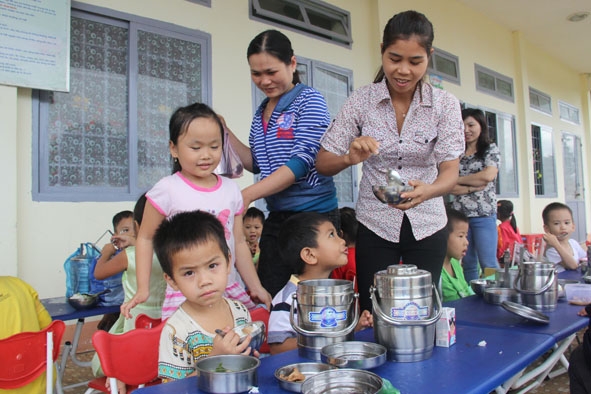 Cô giáo và phụ huynh Trường Mẫu giáo Cư Pui (xã Cư Pui, huyện Krông Bông) cùng chăm bữa ăn trưa cho trẻ. 