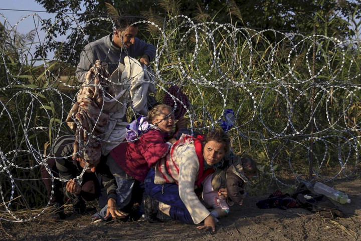 gười di cư Syria chui qua hàng rào khi nhập cảnh vào Hungary tại biên giới với Syria gần Roszke.