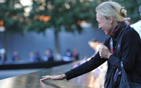 Một thân nhân không kìm được nước mắt khi chạm tay vào tên người thân của mình tại Đài tưởng niệm các nạn nhân vụ 11-9. Ảnh: AP
