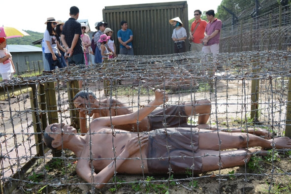 Du khách tham quan  mô hình tái hiện “chuồng cọp kẽm gai” tại Trại giam tù binh Phú Quốc. 