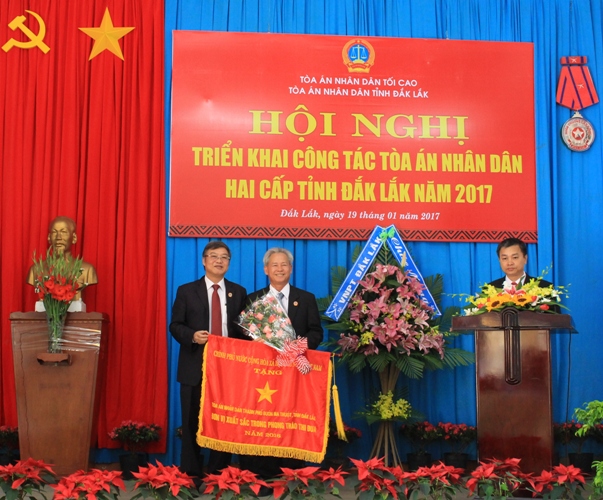 Phó Chánh án TAND Tối cao Nguyễn Sơn (bìa trái) trao Cờ thi đua của Chính phủ tặng TAND TP. Buôn Ma Thuột.