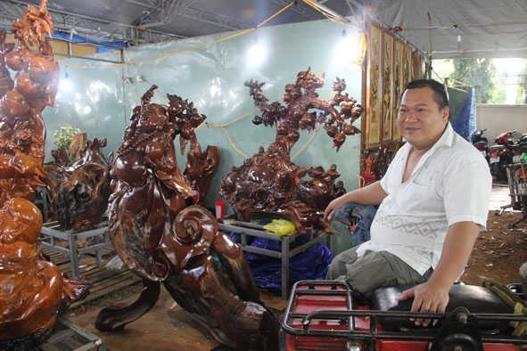 Anh Vĩnh và gian hàng bày bán gỗ mỹ nghệ do cơ sở của anh sản xuất  tham gia Hội chợ Xuân Đắk Lắk 2017. 