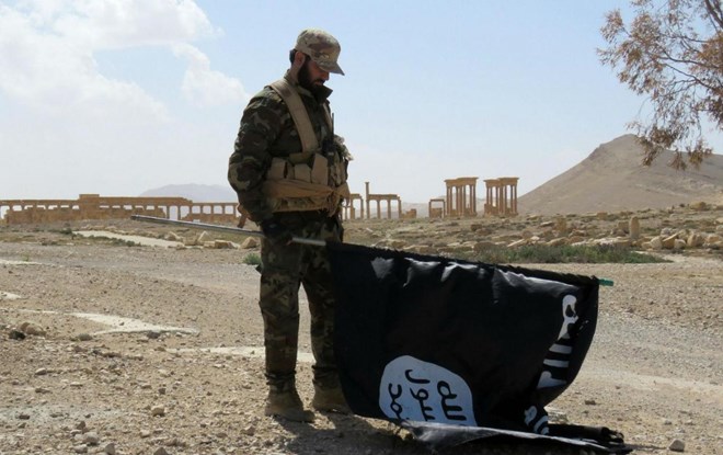 Một binh sĩ Syria hạ lá cờ IS tại thành phố cổ Palmyra (Ảnh: Independent)