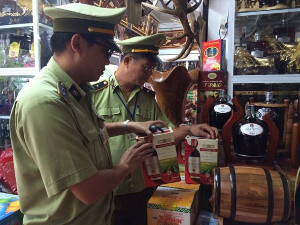 Cán bộ Chi cục QLTT kiểm tra mặt hàng rượu tại một hộ kinh doanh trên đường Lê Thánh Tông (TP. Buôn Ma Thuột).