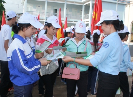 Cán bộ Trung tâm Truyền thông giáo dục sức khỏe phát tờ rơi tuyên truyền về phòng chống tác hại thuốc lá cho học sinh huyện Cư Kuin. 