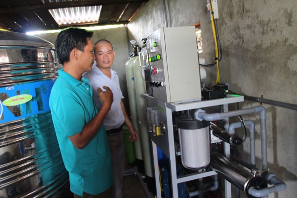 Anh Đàm Văn Dự (bìa trái) đang học cách vận hành hệ thống lọc nước.  