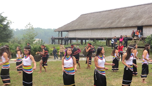 Các thiếu nữ Cor đang múa ka đấu bên mái nhà dài của người Cor tại Làng Văn hóa - Du lịch các dân tộc Việt Nam,  Đồng Mô, Sơn Tây, Hà Nội.  