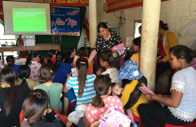 Cán bộ Trung tâm Dân số - KHHGĐ huyện Cư M'gar phát tờ rơi cho người dân tham gia buổi nói chuyện chuyên đề dân số/SKSS-KHHGĐ tại buôn Ajun (xã Ea Kuếh).