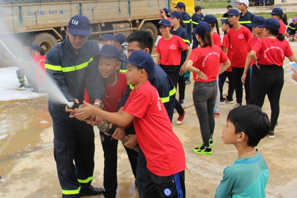 Chiến sĩ Cảnh sát PCCC hướng dẫn các em cách sử dụng lăng vòi chữa cháy.    